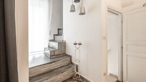 Een trap met houten treden die leidt naar een plateau, een witte deur en een wandlamp.