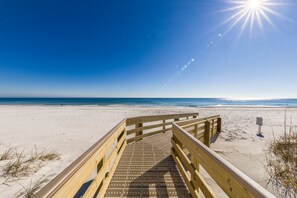 A wooden boardwalk leading to a beach with clear skies and the sun shining. - Island Winds West 870 | Top Floor Views | Heated Pool | Walk to Hangout | Beach Getaways (Gulf Shores)