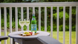 Une table sur laquelle se trouvent une bouteille d’eau Pellegrino, deux verres d’eau et une assiette de fromage et de fruits, le tout posé sur une terrasse blanche.