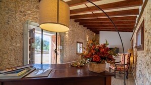 A stone-walled room with a wooden desk, books, a lamp, and a chair. - Es Saquer de Son Coll - with private swimming pool (Algaida)