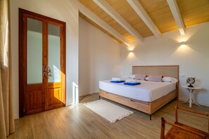A bedroom with a wooden bed, a white rug, a wooden door, and a small table with a globe. - Es Saquer de Son Coll - with private swimming pool (Algaida)