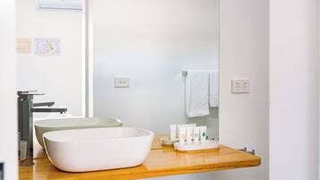 Un bagno con un mobiletto in legno, un lavandino bianco e uno specchio.