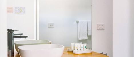Un baño con tocador de madera, un lavabo blanco y un espejo.