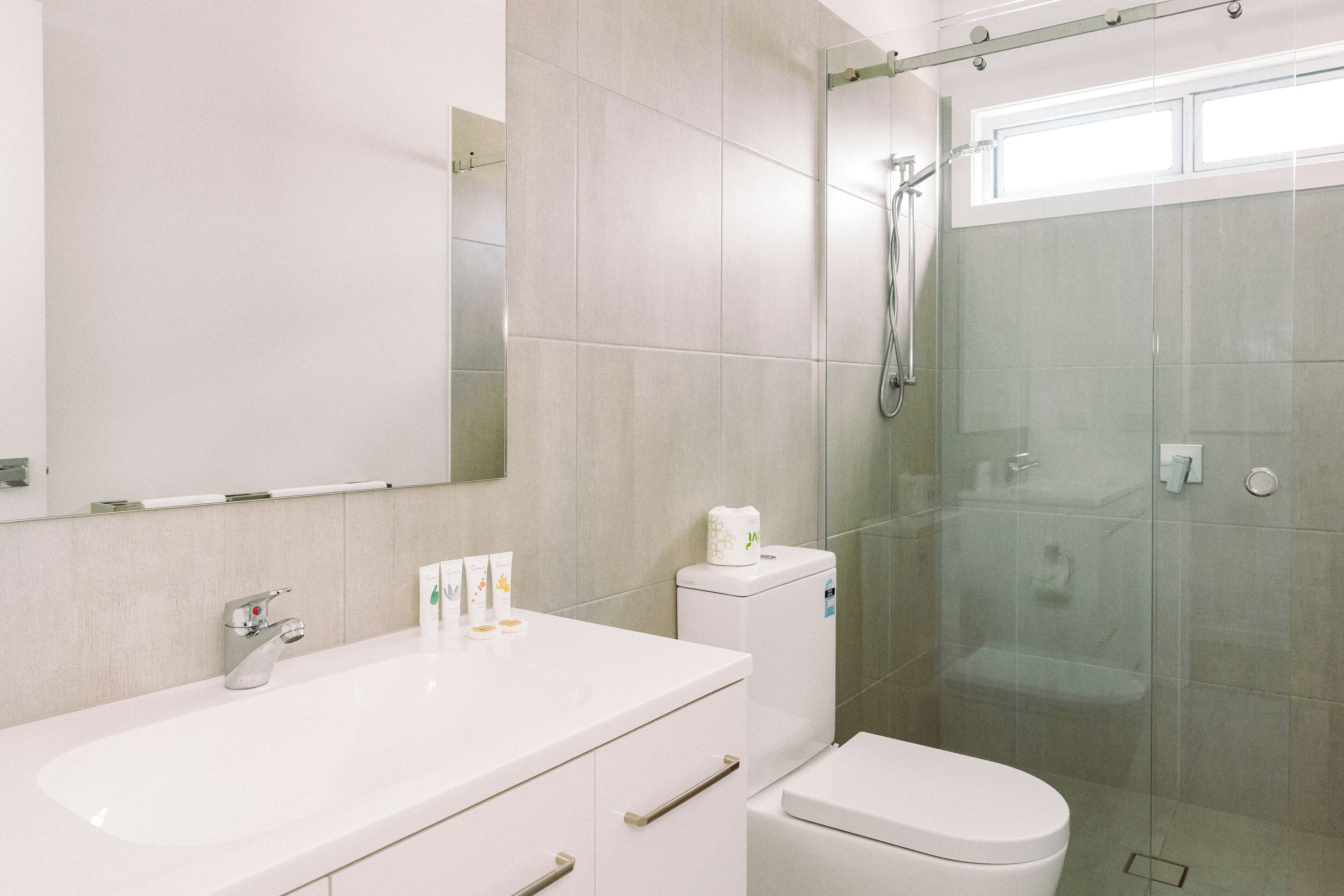 A modern bathroom with a white sink, toilet, and glass-enclosed shower.