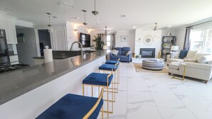Une cuisine moderne avec un îlot central, des tabourets de bar, un canapé et une cheminée.