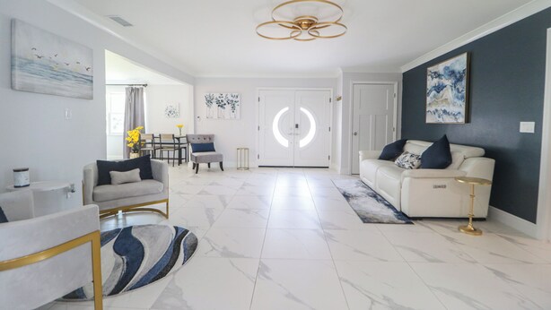 Un salon moderne avec un canapé blanc, un fauteuil gris et un coin repas comprenant une table et des chaises.