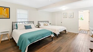 A bedroom with two beds, a window with blinds, a door, and a small table. - scent-free stay - spacious , big yard and safe neighborhood (Imperial)