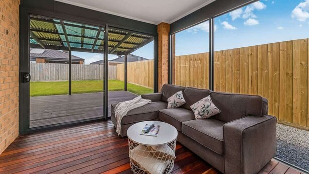 A modern living room with a sectional sofa, a coffee table, and a sliding glass door leading to an outdoor patio.