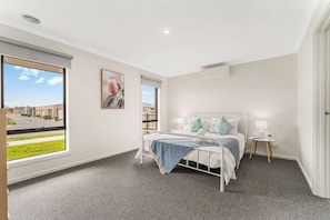 A modern bedroom with a bed, bedside tables, and a window with a view.