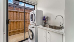 A compact kitchen with a built-in washing machine, a sink, and a sliding glass door leading to a backyard.