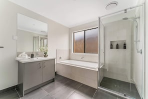 Un bagno moderno con cabina doccia in vetro, un lavabo con specchio e un lavandino.
