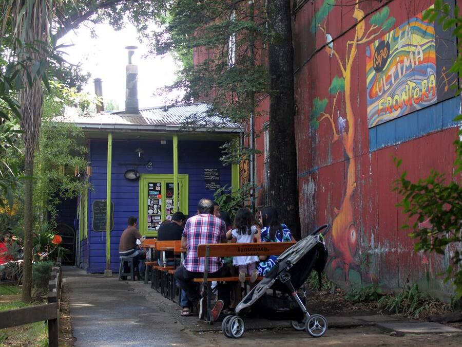 A small outdoor seating area with benches, a covered structure, and a mural on the wall.