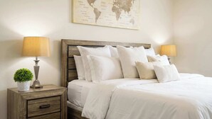 A neatly made bed with white bedding, a wooden headboard, and two bedside lamps.