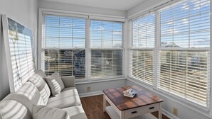A bright room with a sofa, a small table, and large windows with blinds.