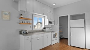 A modern kitchen with white cabinets, a microwave, a toaster, and a refrigerator.