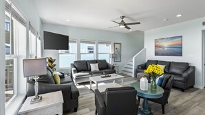 A modern living room with a grey sofa, a coffee table, and a TV mounted on the wall. - Beachfront | Spacious, Pet-Friendly & Relaxing (Gilchrist)