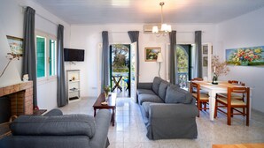 Una sala de estar moderna con chimenea, sofás grises, una mesa de comedor con sillas y un televisor montado en la pared.