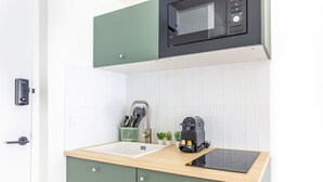 A kitchen with a microwave, coffee machine, and utensils on the counter. - Lavie Maison: Equipped Studio, Chartrons (Bordeaux)