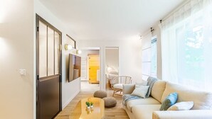 Een moderne woonkamer met een bank, salontafel en een aan de muur bevestigde televisie.