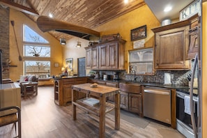 A spacious kitchen with wooden cabinets, a central island, and a dining area with a table and chairs.