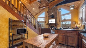 Une cuisine spacieuse avec des meubles de rangement en bois, une table à manger en bois et une étagère intégrée pour le micro-ondes.