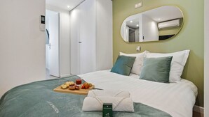 Ein Hotelzimmer mit Bett, Frühstückswagen, Handtuch und Spiegel.