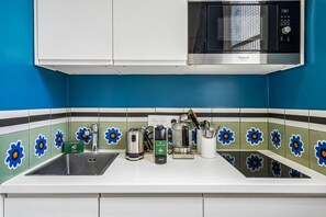 Uma cozinha com micro-ondas, torradeira, chaleira e cafeteira no balcão.