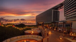 Una terraza en la azotea con un área de estar semicircular, un brasero y vistas a un edificio moderno.