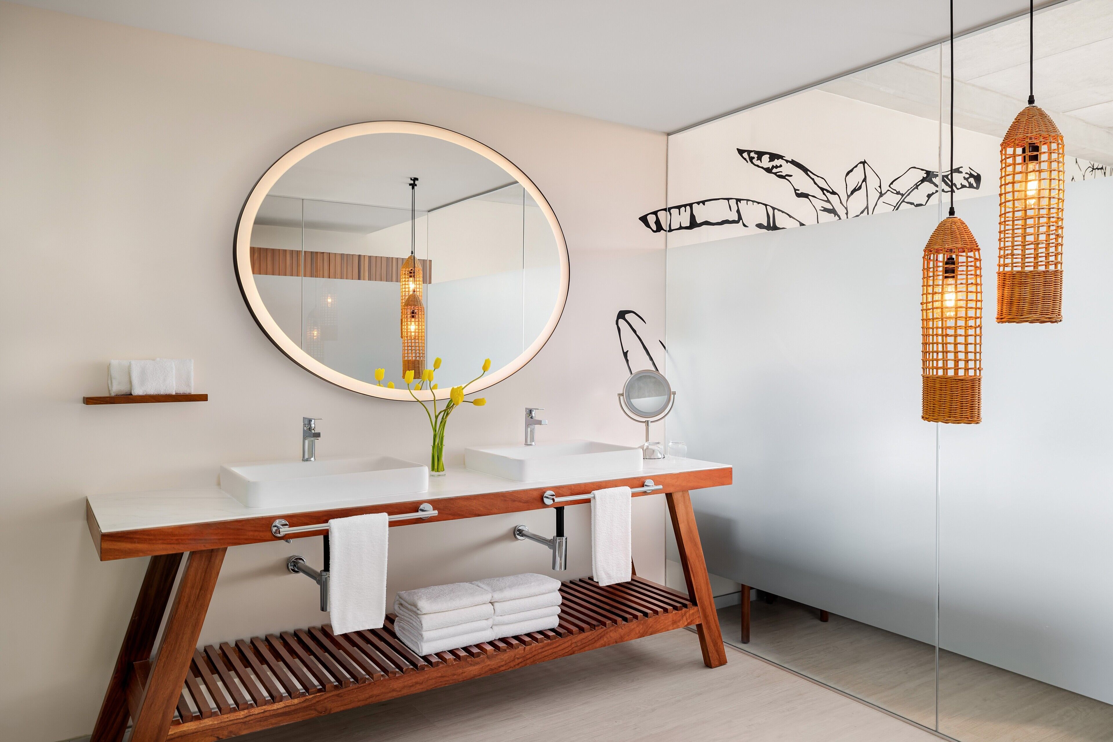 A modern bathroom with a wooden vanity, two sinks, a large mirror, and decorative wall art.