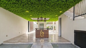 A reception area with a green artificial ceiling, a wooden reception desk, and a marble floor.