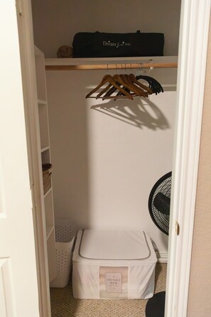 A closet with a hanging rack, a suitcase, and a storage box labeled 'TRUNDLE BED'.