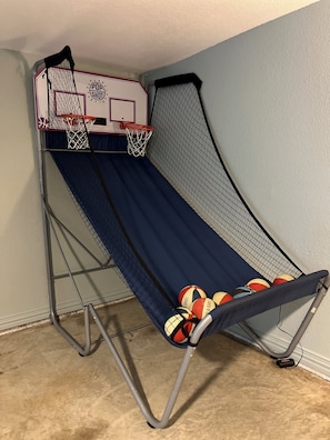 Un panier de basket portable, muni d’un filet et d’un panneau, une glissoire bleue et plusieurs ballons de basket.