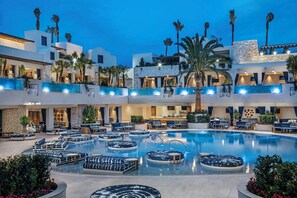 Un hotel de varios niveles con una piscina central rodeada de zonas de descanso y asientos.