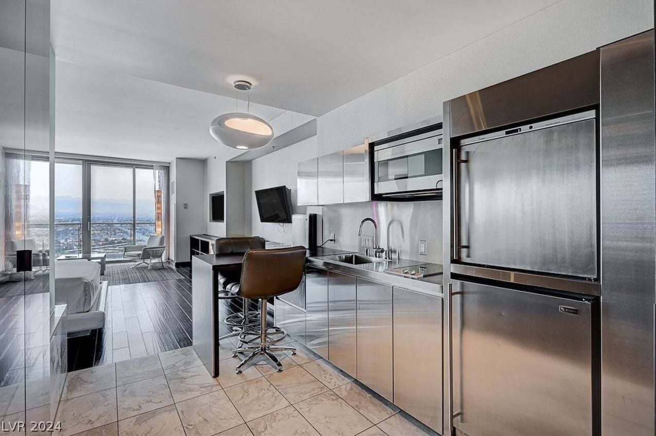 A modern kitchen with stainless steel appliances, a bar area, and a city view.