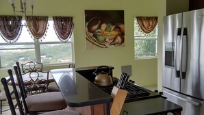 Een keuken met een centraal eiland, een koelkast, een fornuis en een eethoek met stoelen en een tafel.