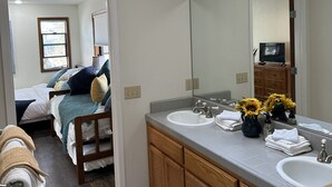 A modern bathroom with a skylight, dual sinks, and a large mirror.
