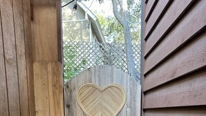 A wooden gate with a heart-shaped cutout, a wooden fence, and a paved walkway.