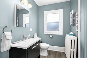 A bathroom with a white sink, a mirror, a toilet, and a radiator. - Cozy Lakeside Studio in Duluth with queen bed, Wi-Fi, parking, and full kitchen. (Duluth)