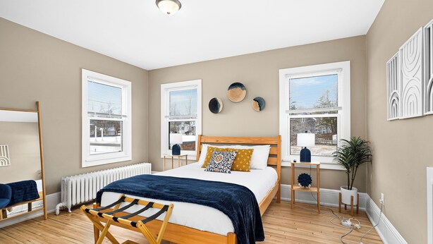 A bedroom with a wooden bed, a window with blinds, a radiator, and a plant. - Lakeside Studio | Minutes from Downtown Duluth (Duluth)