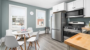 A modern kitchen with white cabinets, stainless steel appliances, and a wooden dining table. - Lakeside Studio | Minutes from Downtown Duluth (Duluth)