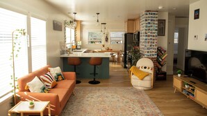 A modern living room with a sofa, a coffee table, and a TV stand. - The Biggest Little House in Reno Midtown! Cozy Home Theatre  & Backyard BBQ (Reno)