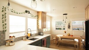 A modern kitchen with a large island, wooden cabinets, and a dining area with a bench. - The Biggest Little House in Reno Midtown! Cozy Home Theatre  & Backyard BBQ (Reno)