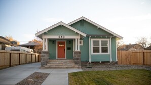 A single-story house with a green exterior and a red door, featuring a stone foundation and a number '530' displayed above the entrance. - The Biggest Little House in Reno Midtown! Cozy Home Theatre  & Backyard BBQ (Reno)