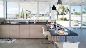 Una cocina moderna con una isla grande, un comedor con vistas y una piscina afuera.