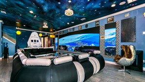 Ein modernes Wohnzimmer mit einer großen Unterhaltungseleinrichtung, einer Sternenhimmel-Decke und einer gemütlichen Sitzecke.