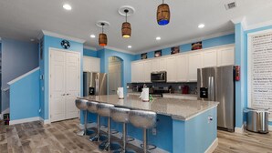 Una cocina moderna con paredes azules, electrodomésticos de acero inoxidable y una barra con taburetes.