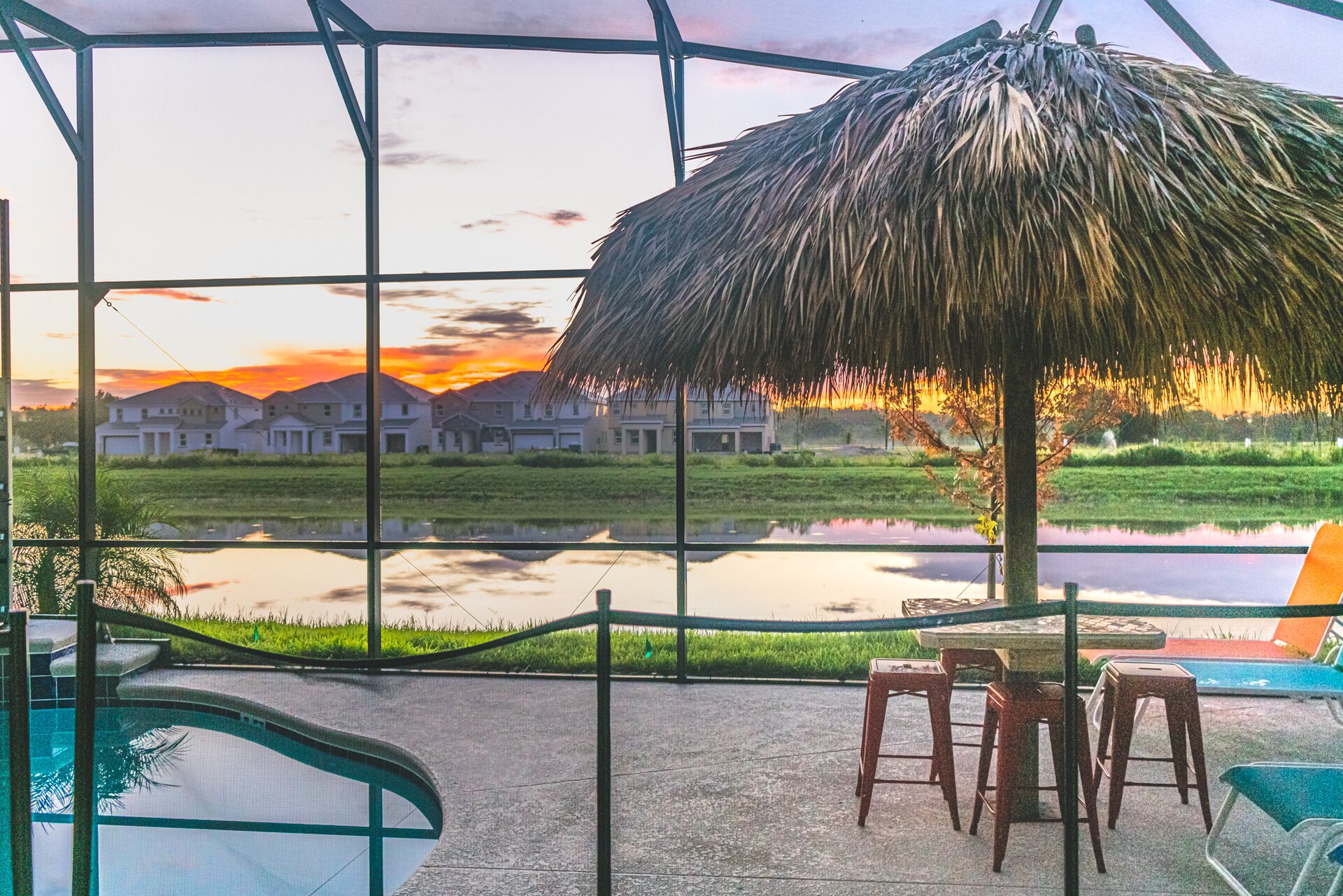 A pool area with a view of houses and a sunset.