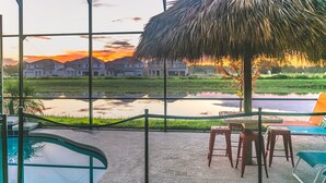 A pool area with a view of houses and a sunset.