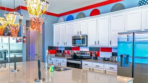 A modern kitchen with white cabinets, stainless steel appliances, and a colorful backsplash.