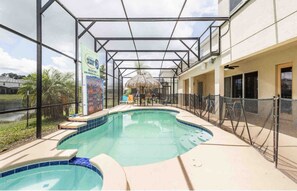 A covered outdoor swimming pool with a pergola and a thatched umbrella, surrounded by a fence. - Sports Bowling Home, Orlando Mansion 6229 (Orlando)